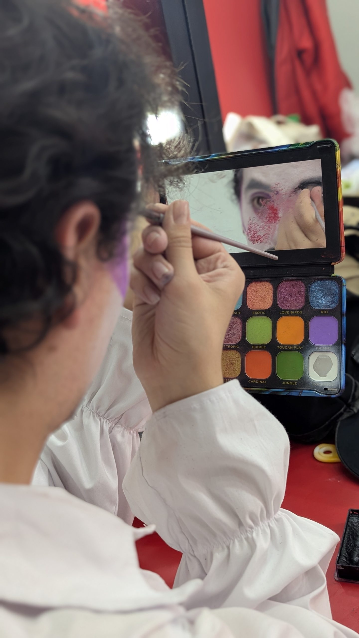 Proceso de maquillaje artístico en el camerino de la obra