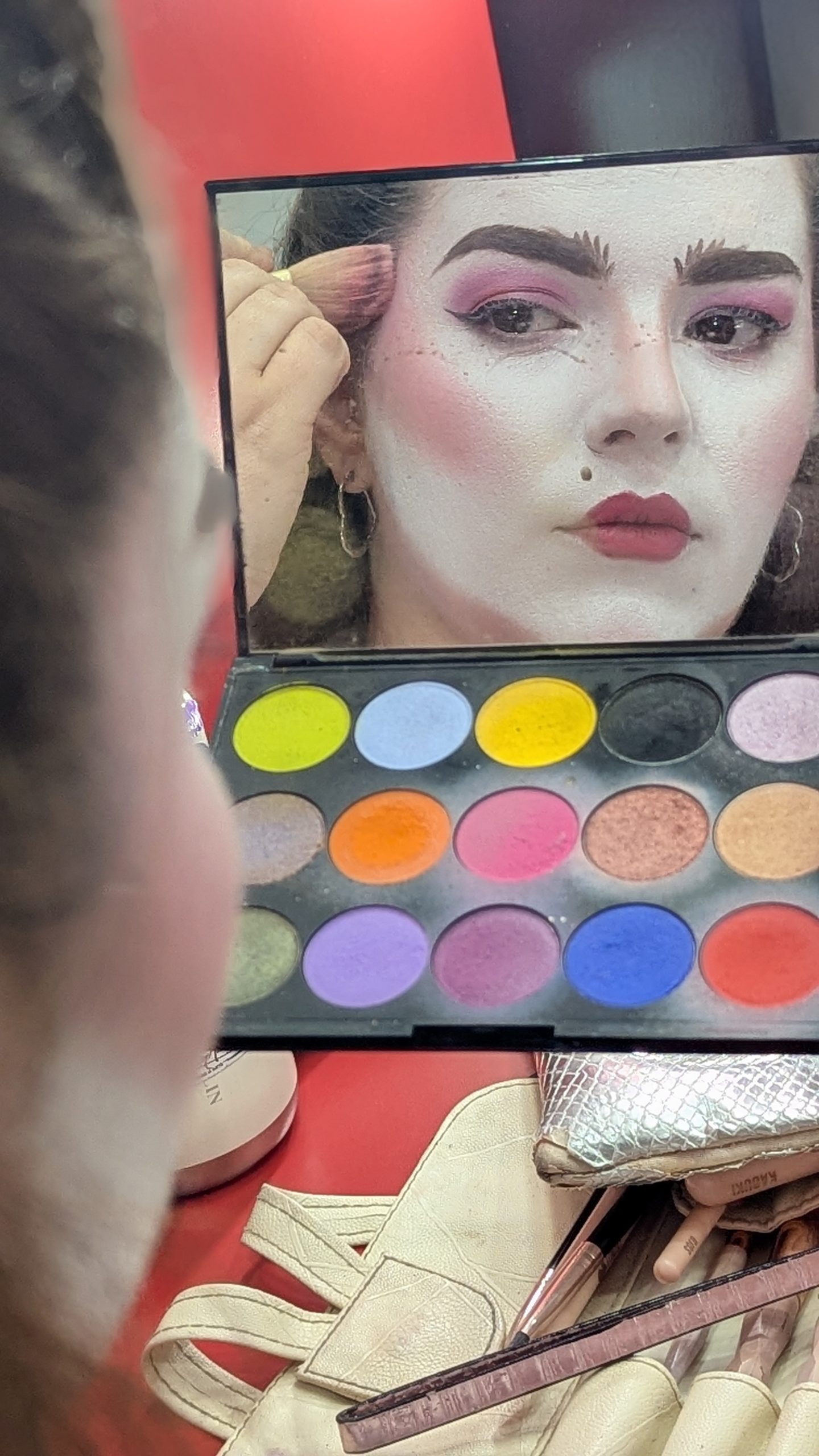 Reflejo de una actriz y paleta de colores durante el maquillaje